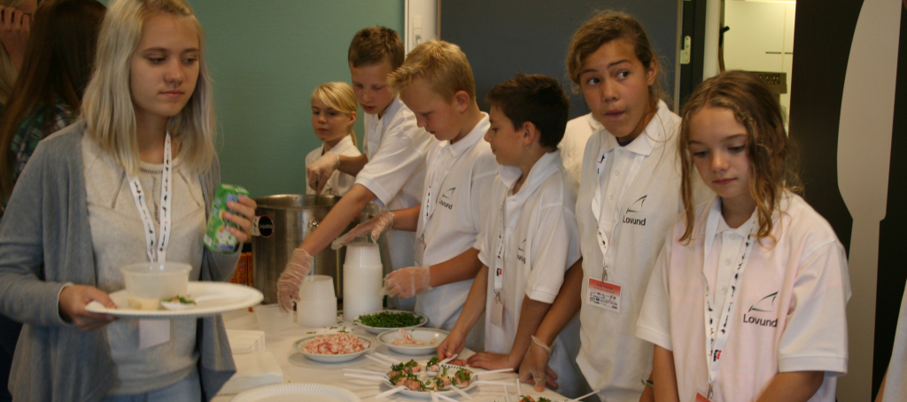 Elevene fra 6. og 7. klasse på Lovund serverer laks i ulike varianter til 10. klassingene fra hele Helgeland. Foto: Ø. Haram/FHL.